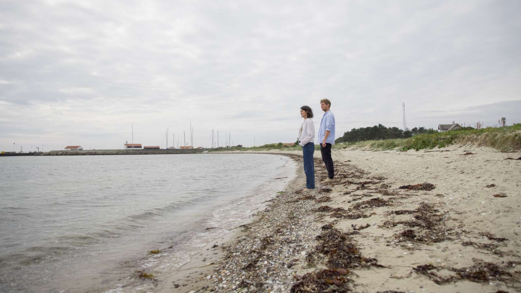 A couple stands on the beach on Tunø, looking out over the sea