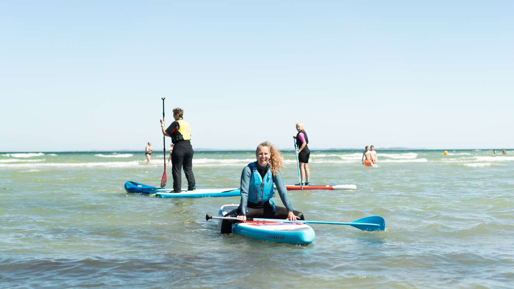 Three people on SUP boards in the water at Saksild Strand