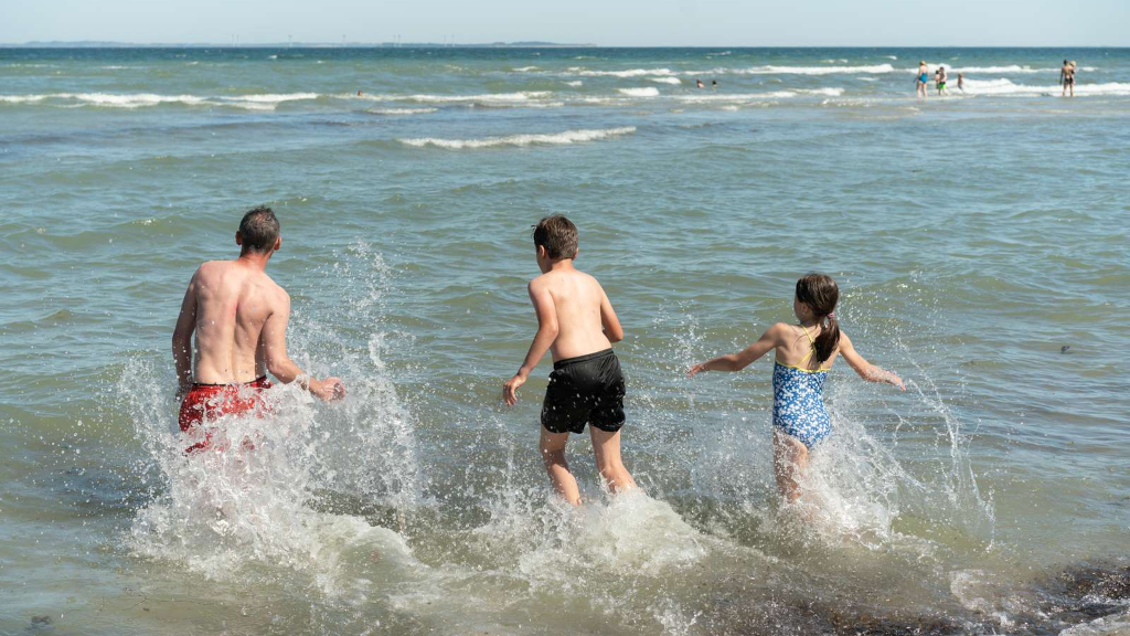 A family running into the water at Saksild Strand