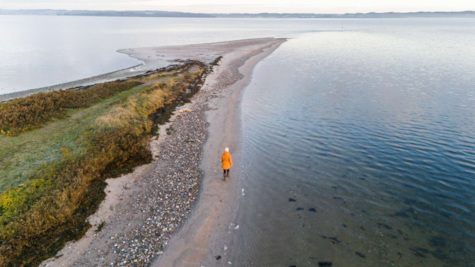 Kvinde går på stranden på Borre Knob