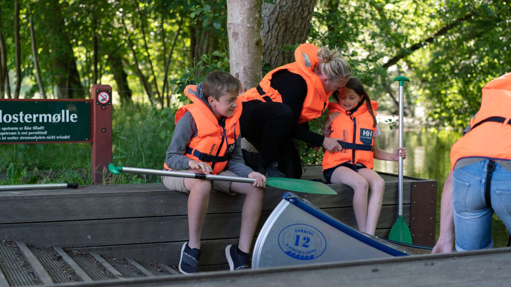 A family sitting by a canoe at Klostermølle