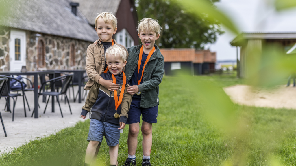 Three boys with medals from the treasure hunt on Hjarnø