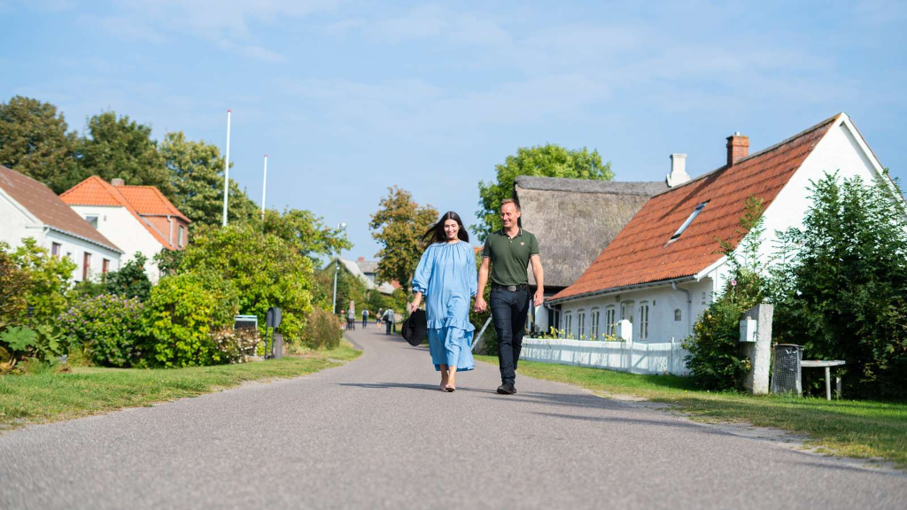 A couple is walking on a road through the village on Tunø