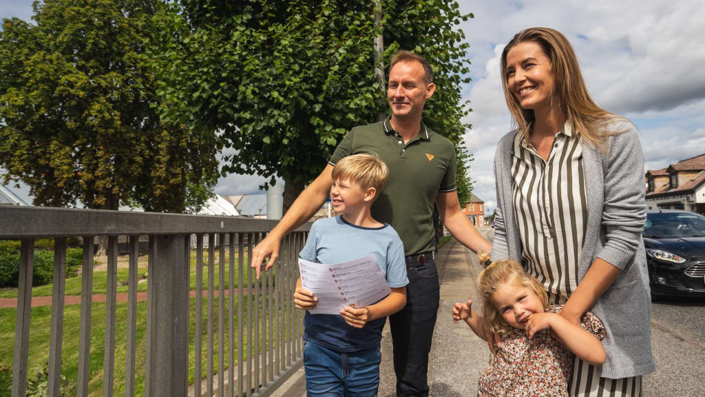 Family walking on the sidewalk in Odder with a treasure map from the Odder Treasure Hunt
