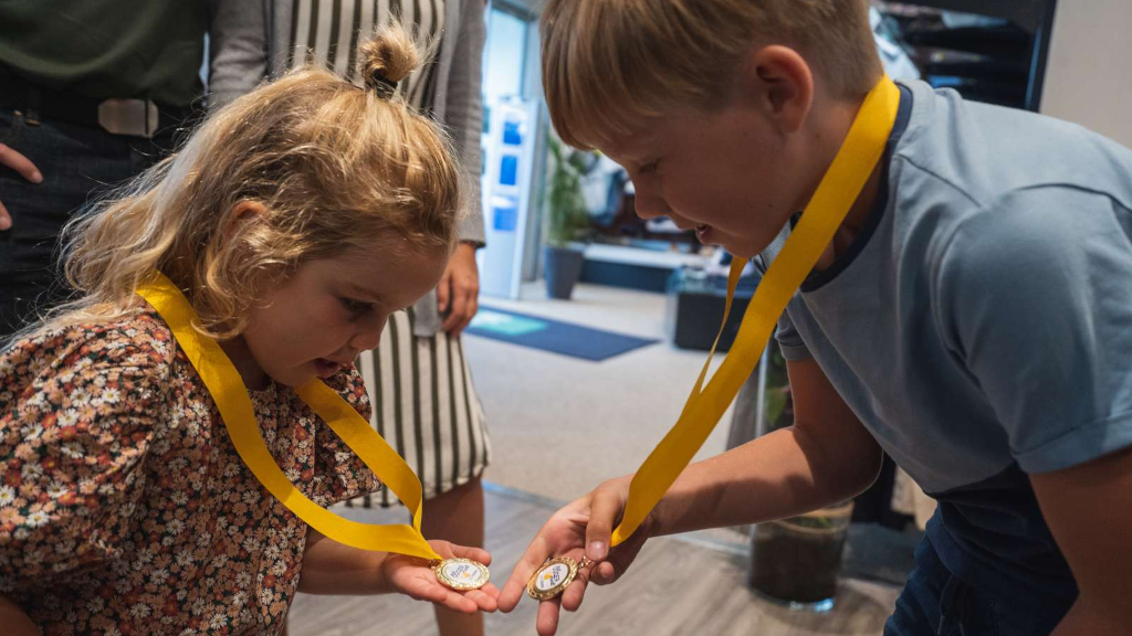 A boy and a girl looking at their medals from the Odder Treasure Hunt