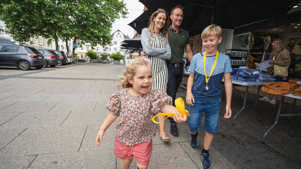 Family walking at the town square in Odder with medals from The Odder Treasure Hunt