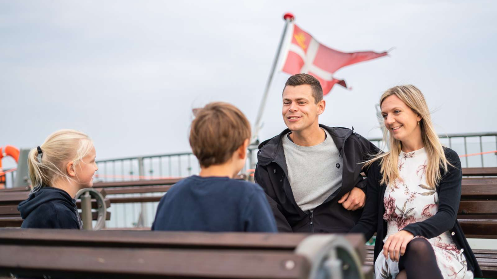 A family sits on a bench on the deck of the Endelave ferry