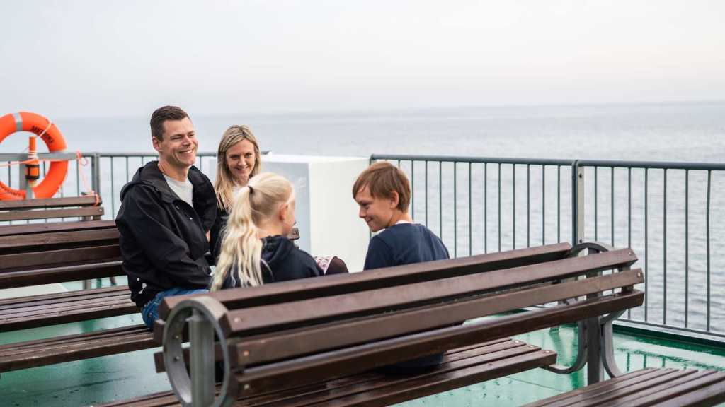A family sits on a bench on the deck of the Endelave ferry