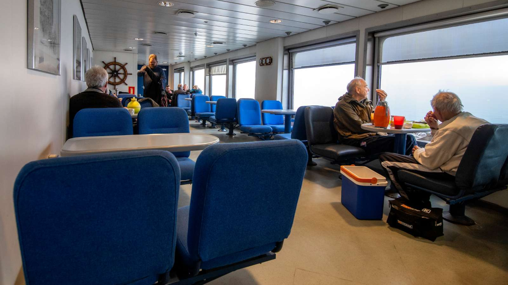 Passengers are seated on chairs in the Endelave ferry