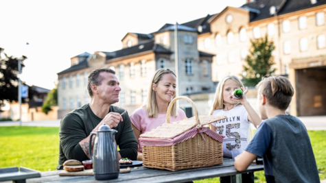 En familie spiser frokost ved en bænk i Fængselsparken ved FÆNGSLET i Horsens