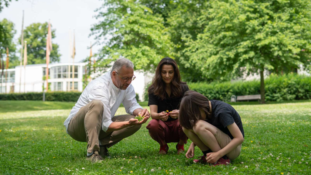 Familie sidder i græsset og kigger på blomster i Caroline Amalie Lund i Horsens