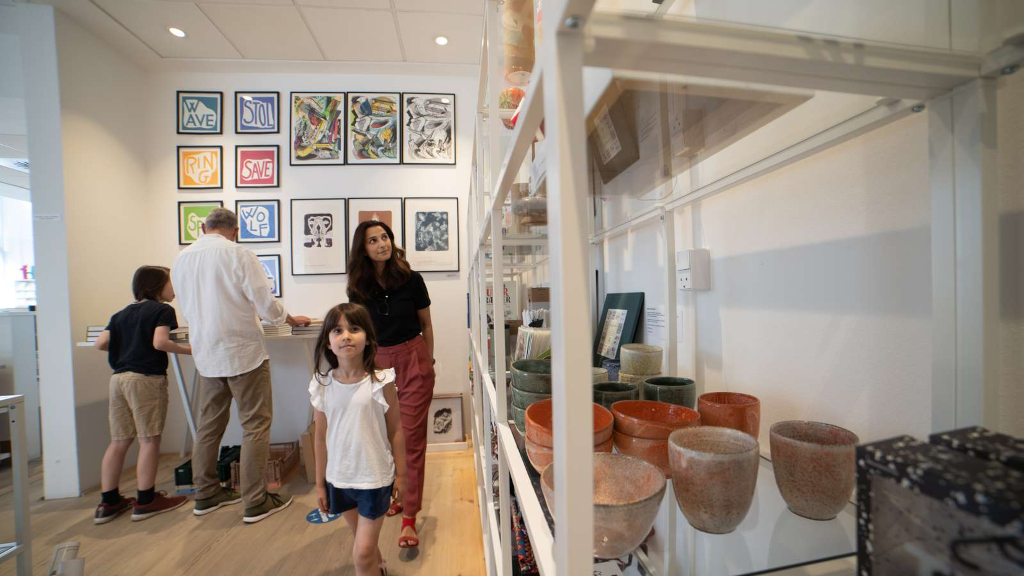En familie kigger på krukker og plakater i butikken hos Horsens Kunstmuseum