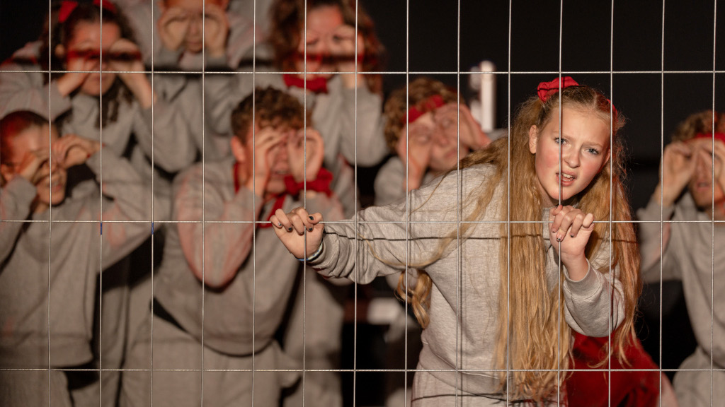 A theater group stands by a fence during a performance at the Horsens Teater Festival