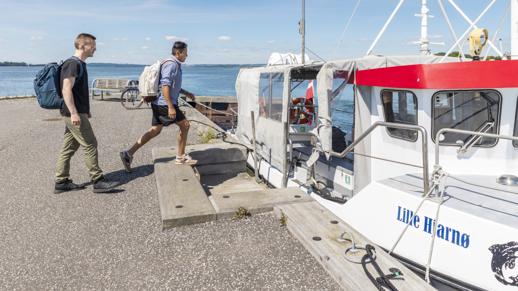 Two men with backpacks boarding the Alrø-Hjarnø Bicycle Ferry on Hjarnø