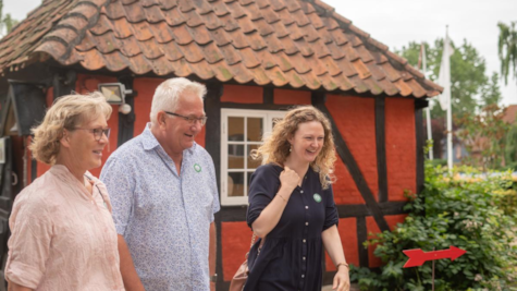 En kvinde og hendes forældre går foran bindingsværkshus ved Glud Museum