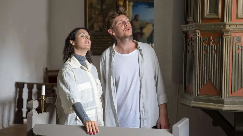 A couple standing in front of the pulpit in Endelave Church, looking
