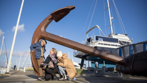 En familie kigger på et skattekort ved Fregatten Jyllands anker i Juelsminde