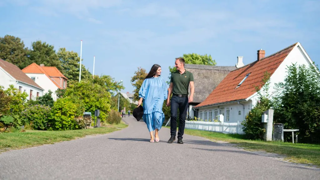 Et par går ned gennem Tunø Hovedgade mellem gamle huse