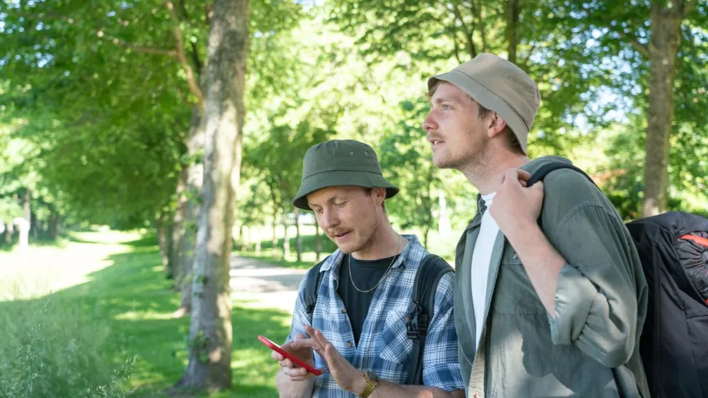 Two men are standing in Palsgaard Castle Park and looking at a phone