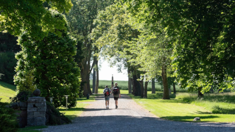 To mænd går på allé i retning af monument i Palsgaard Slotspark