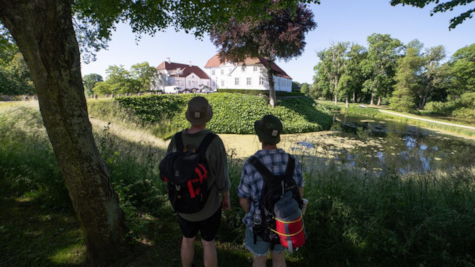 To mænd står ved voldgrav i Palsgaard Slotspark og kigger på Palsgaard Slot