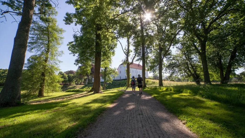 Men are walking on a path in the park towards Palsgaard Castle
