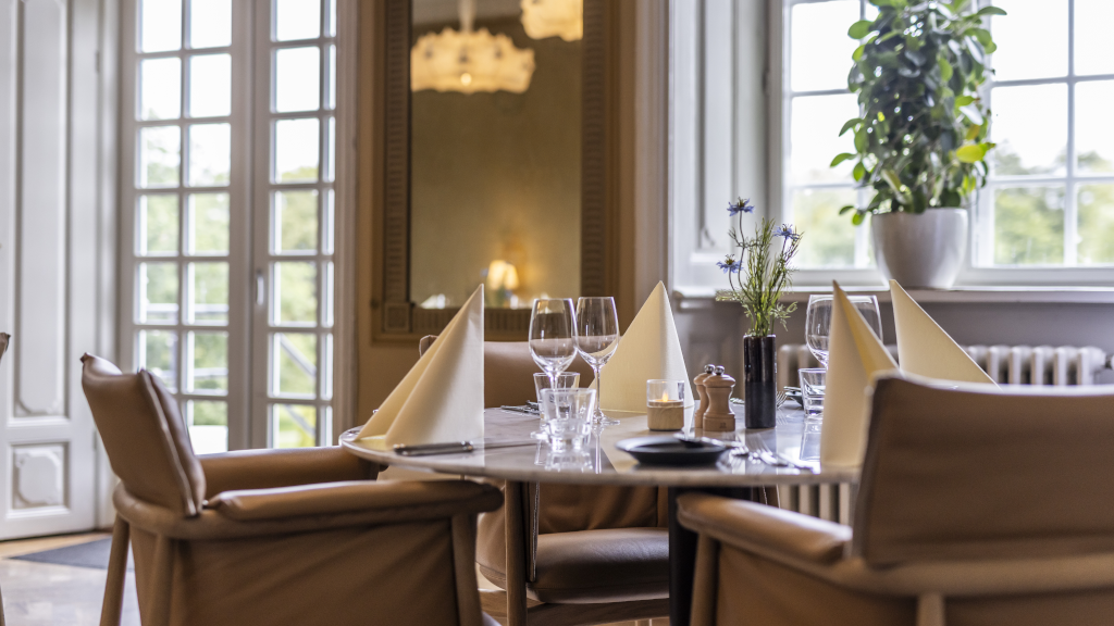 A round table with comfortable chairs in Restaurant Bygholm overlooking Bygholm Park