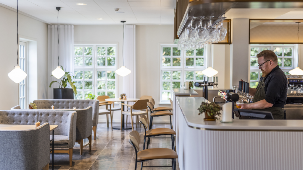 A waiter is standing at the bar at Comwell Bygholm Park