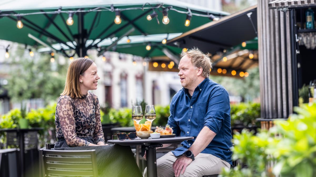 A couple is sitting outdoors at Restaurant Eydes with wine and snacks