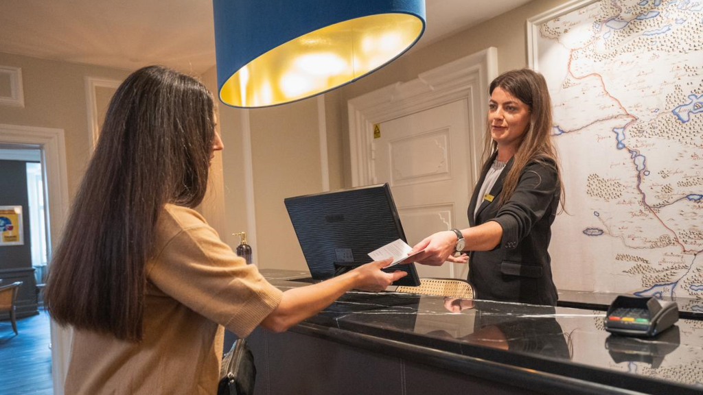 A woman receives a key at the reception at Jørgensens Hotel