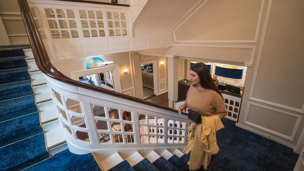 A woman walks up the stairs in the lobby at Jørgensens Hotel