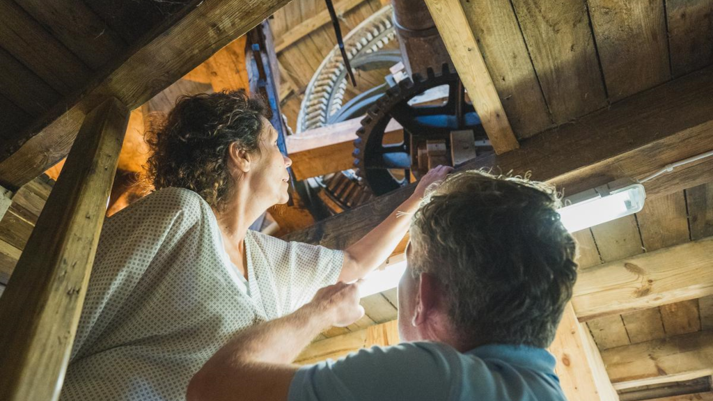 A couple stands on a staircase, studying the mechanics of Uldum Mill