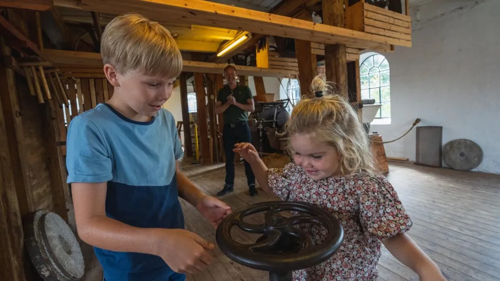 Børn drejer et hjul i møllen på Odder Museum