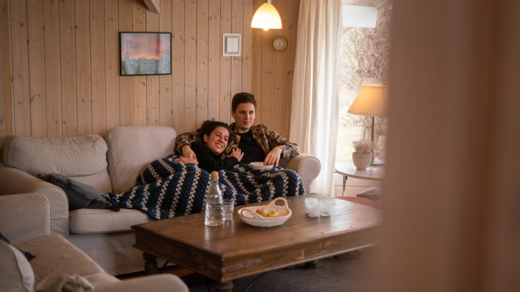 A couple is sitting on a sofa in a holiday home, holding each other