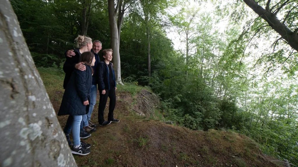 A family is standing on a slope in Staksrode Forest, looking out over the sea