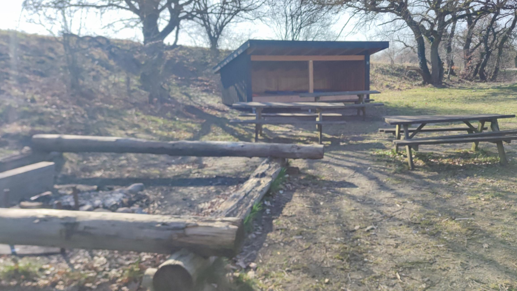 Fire pit and table/bench set in front of a shelter at the shelter site in Lundum