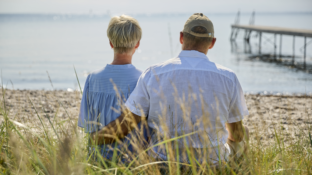 A couple is sitting in the sand at Hølken Beach, holding each other while looking out at the Kattegat