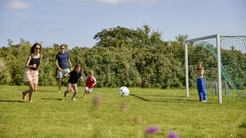 A family is playing football on the football field at Hygge Strand Camping