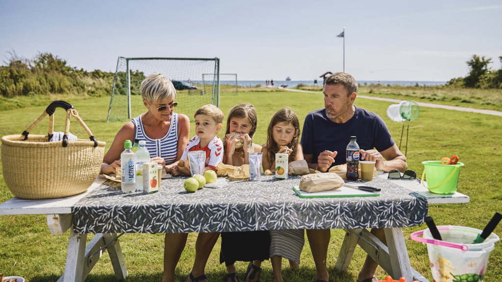 A family is having lunch at a bench at Hygge Strand Camping