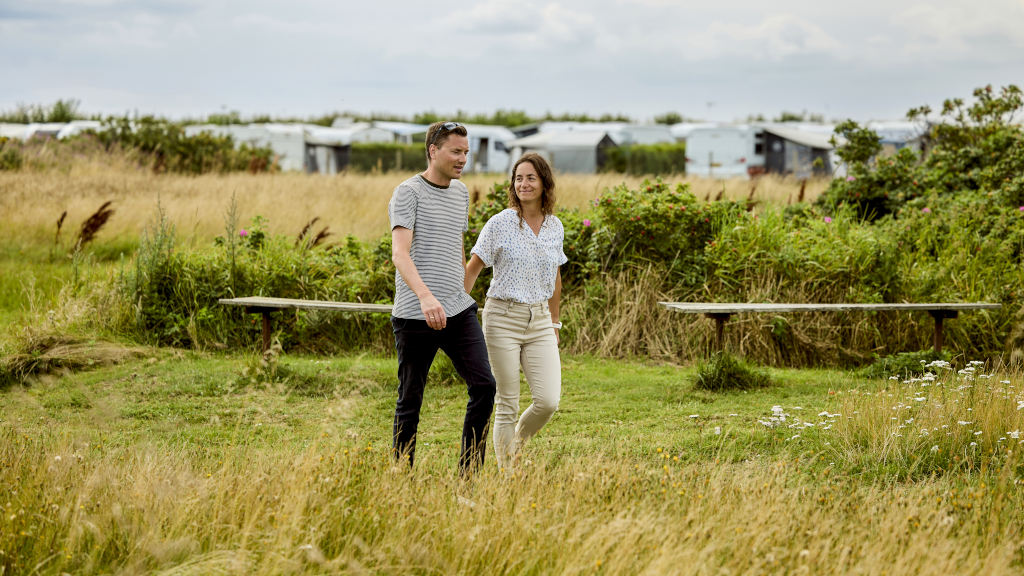 A couple is walking on the lawn at Hygge Strand Camping