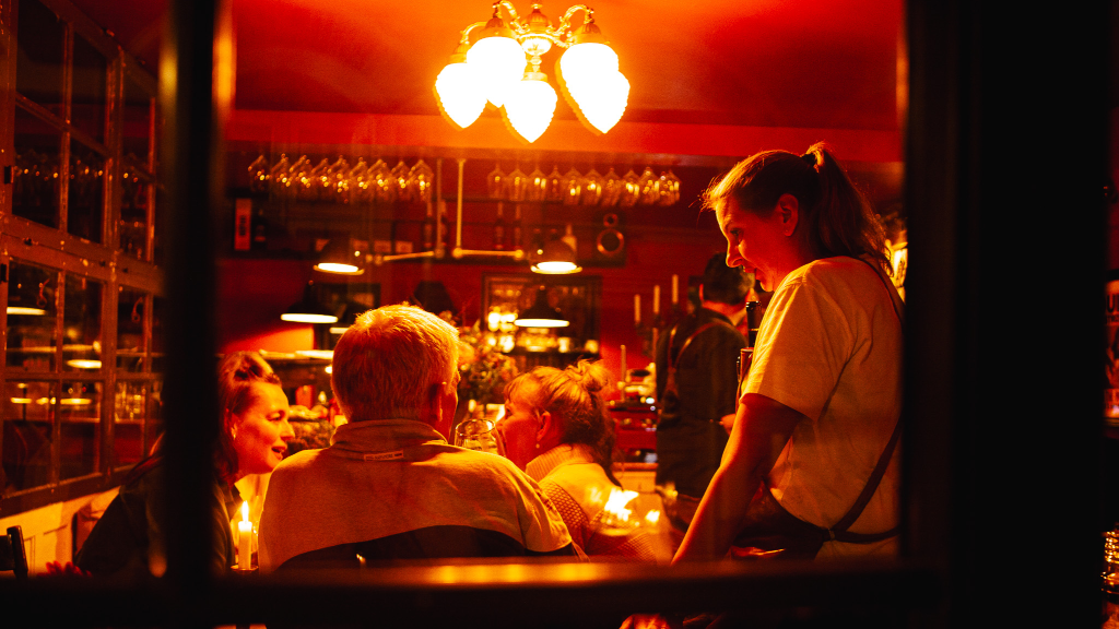 Tjener tager imod ordre fra kunder i Vores Lille Vinbar i Horsens