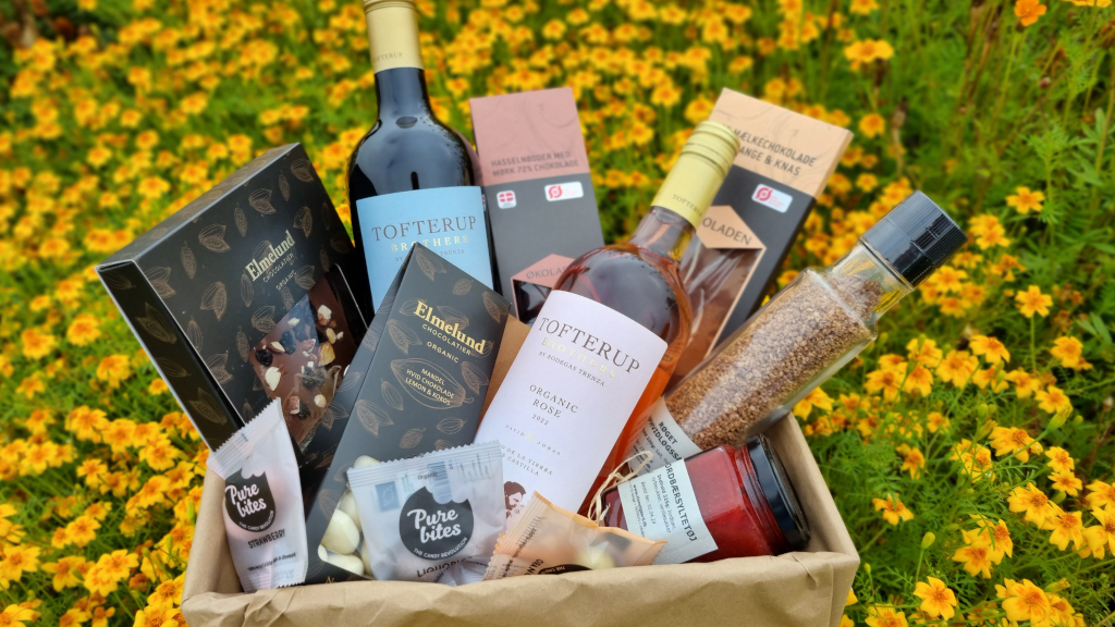 A gift basket with specialties from the Tinnetgaard farm shop placed in a flower meadow