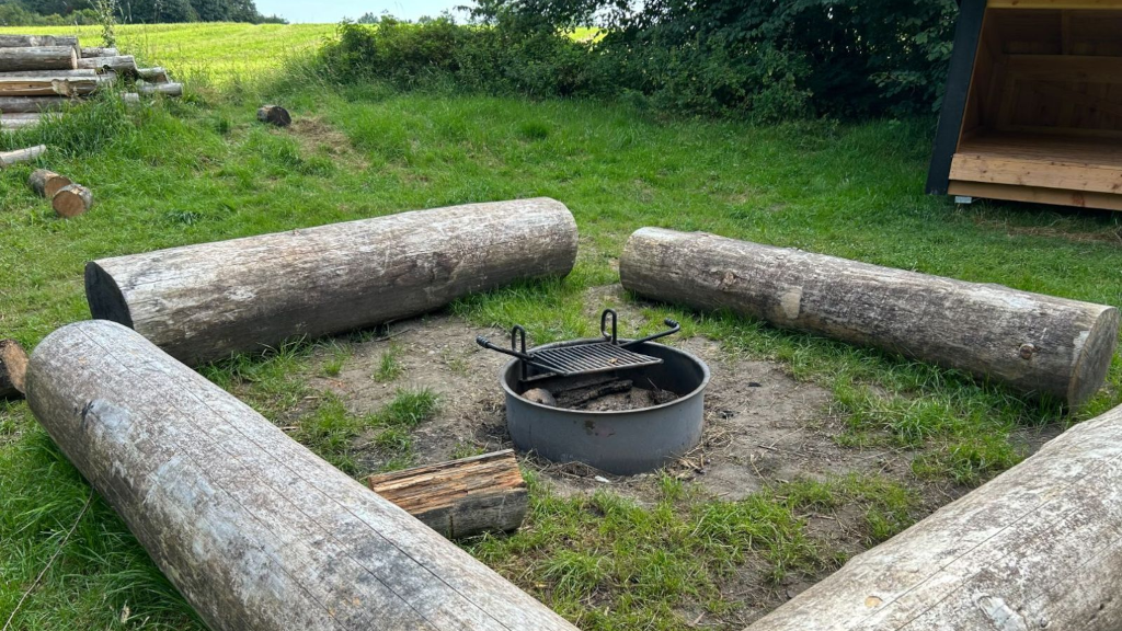 A fire pit at a shelter site by a field