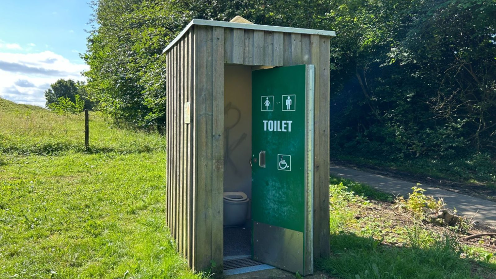A composting toilet at a shelter site by a field