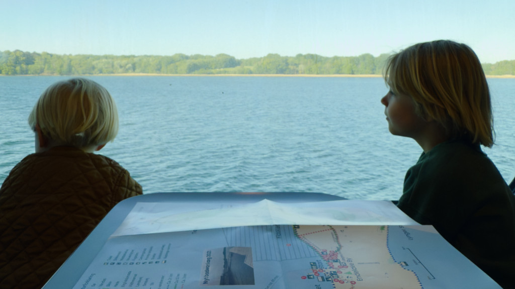 Two boys sitting on the Endelave Ferry, looking out the window at the sea