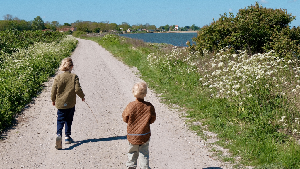 Two boys walking on a gravel path along the water on the Kanino trail on Endelave