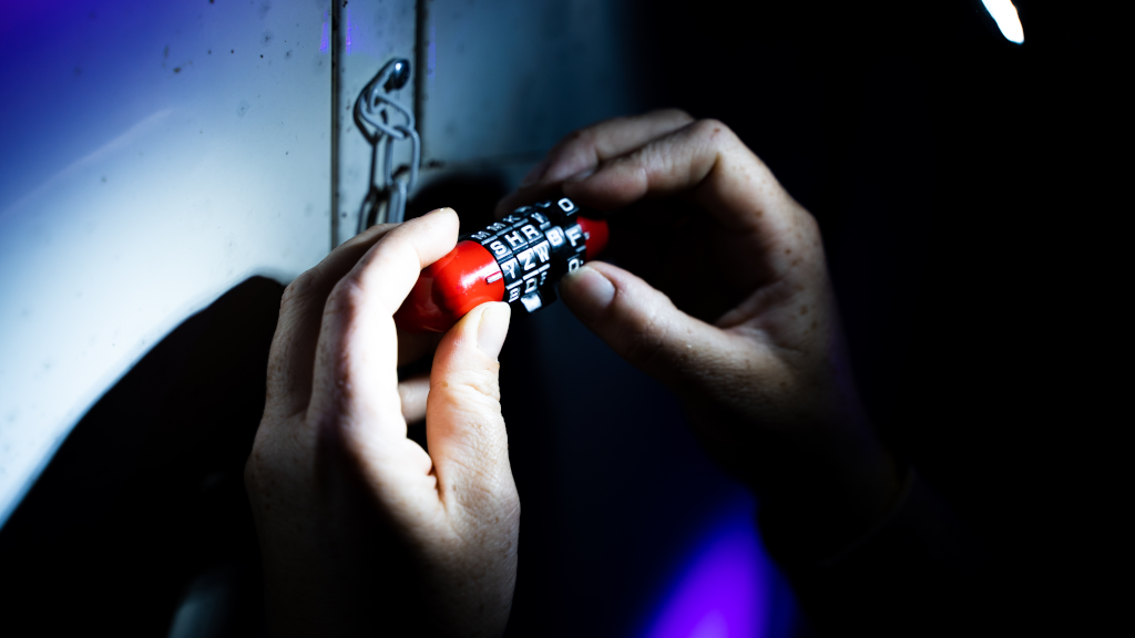 Hands on a combination lock in a dark room at Locked Escape Rooms in Horsens