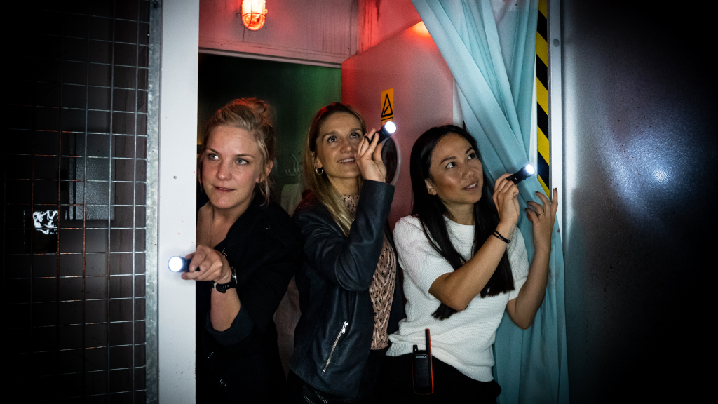 Female friends are looking into a dark room at Locked Escape Rooms in Horsens