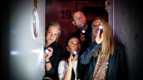 En gruppe venner kigger ind i et rum med lommelygter hos Locked Escape Rooms FÆNGSLET