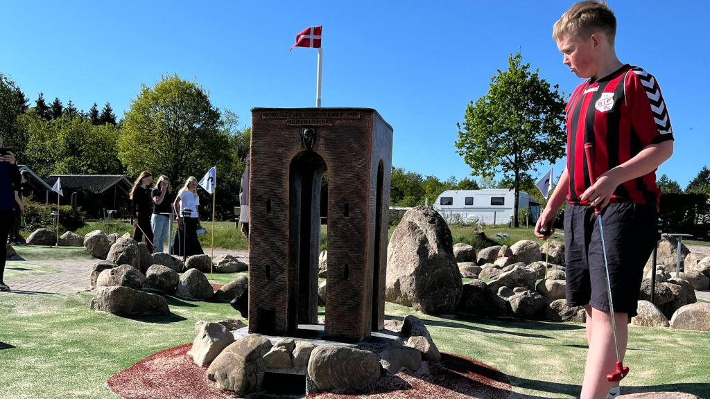 Junge betrachtet eine Miniaturausgabe des Ejer-Bavnehøj-Turms auf dem Minigolfplatz bei Gudenå Camping